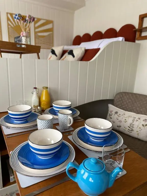 a table with blue and white bowls and plates on it at Ledmacoy Shepherds Huts in Strathdon