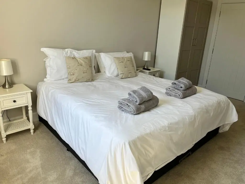 a bedroom with a large white bed with towels on it at Dune House, Golf Road, Dornoch 5x Bedrooms in Dornoch