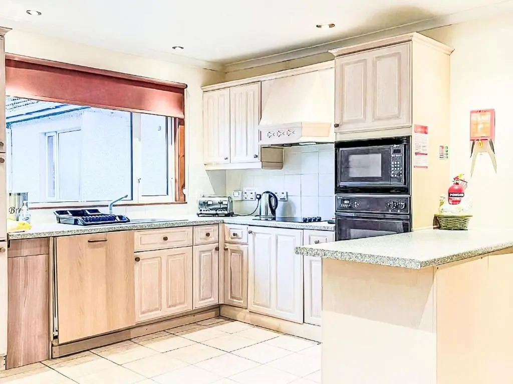 a kitchen with white cabinets and a large window at Chalet Oich View by Interhome in Spean Bridge