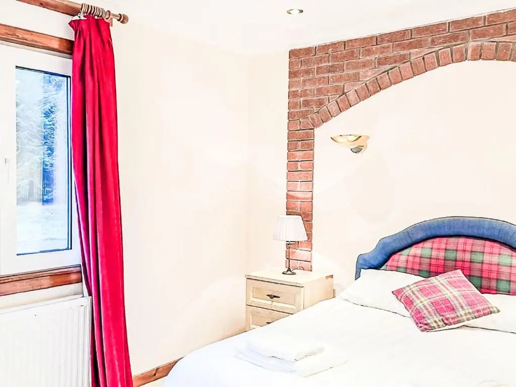 a bedroom with a bed with a red curtain at Chalet Oich View by Interhome in Spean Bridge
