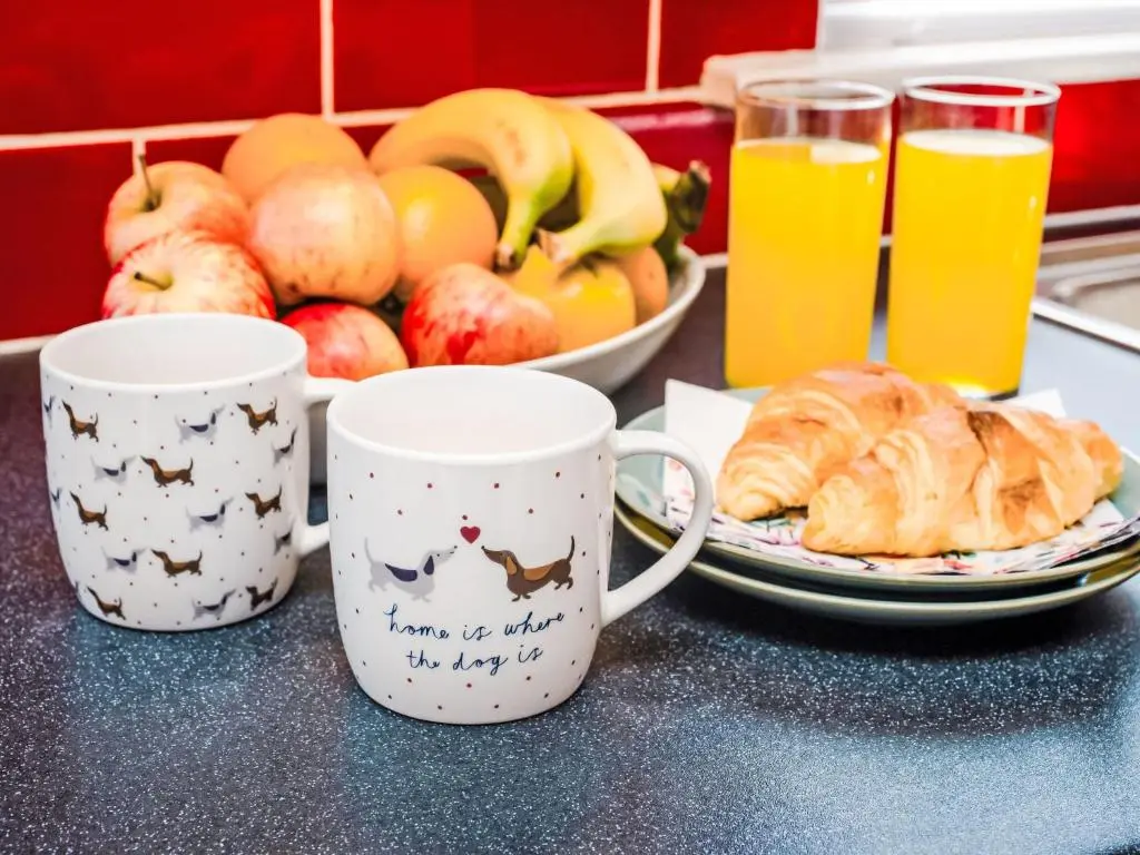 two coffee mugs sitting on a table with a plate of fruit at Holiday Home Kincraig by Interhome in Inverness