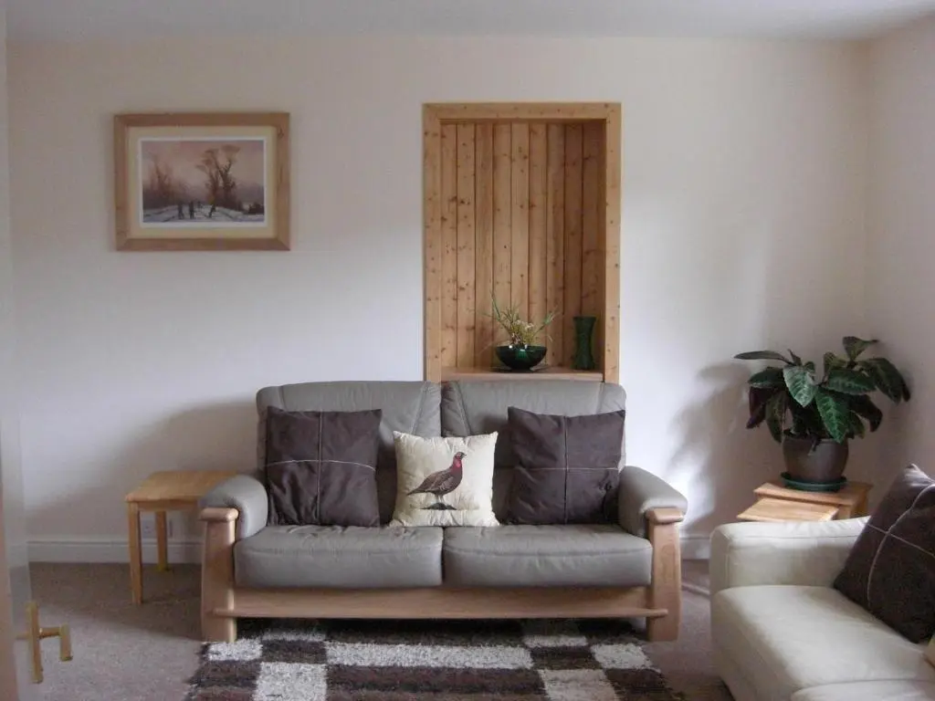 a living room with a gray couch with two pillows at Seggat Farm Holiday Cottages in Kirktown of Auchterless