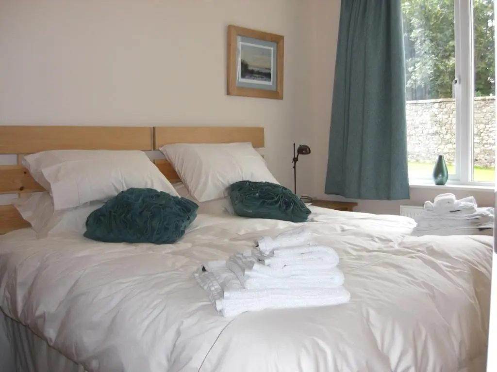 a white bed with two pillows and towels on it at Seggat Farm Holiday Cottages in Kirktown of Auchterless