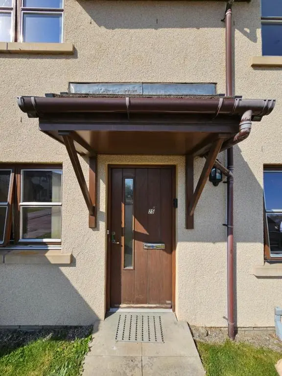 a house with a wooden door with awning at Modern Dornoch Apartment in Dornoch