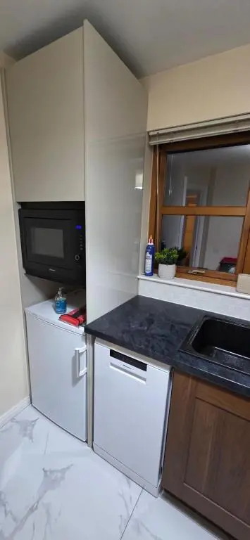 a small kitchen with a sink and a microwave at Modern Dornoch Apartment in Dornoch