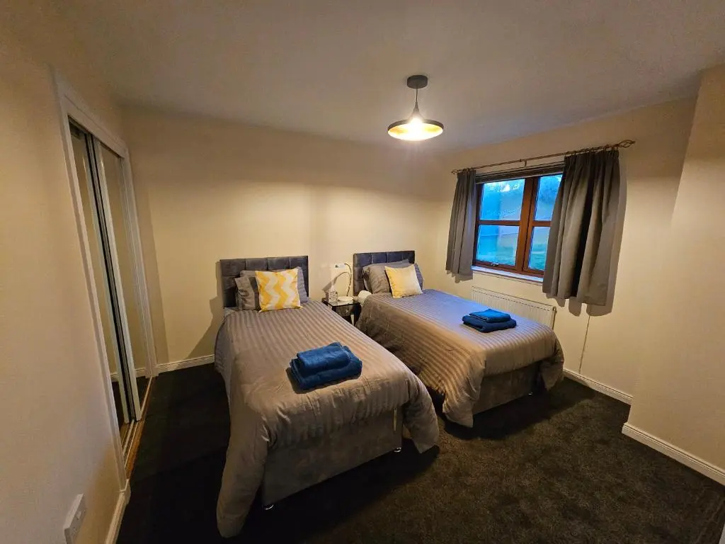 a bedroom with two beds with blue pillows on them at Modern Dornoch Apartment in Dornoch