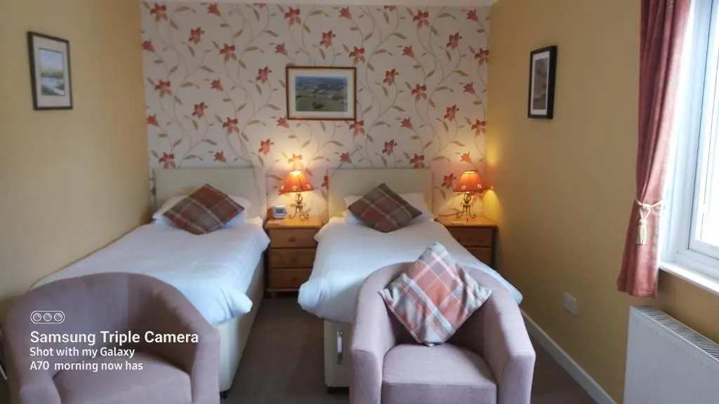 a room with two beds and a chair in it at Ornum House in Beauly