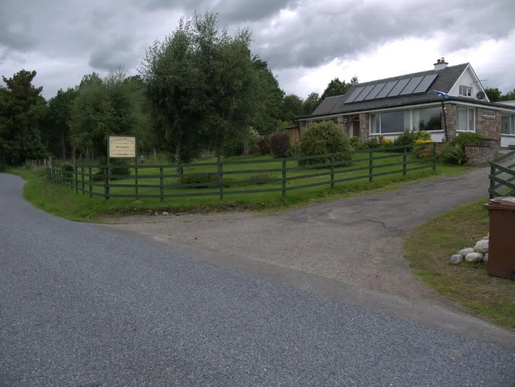 a house with a fence on the side of a road at Ornum House in Beauly