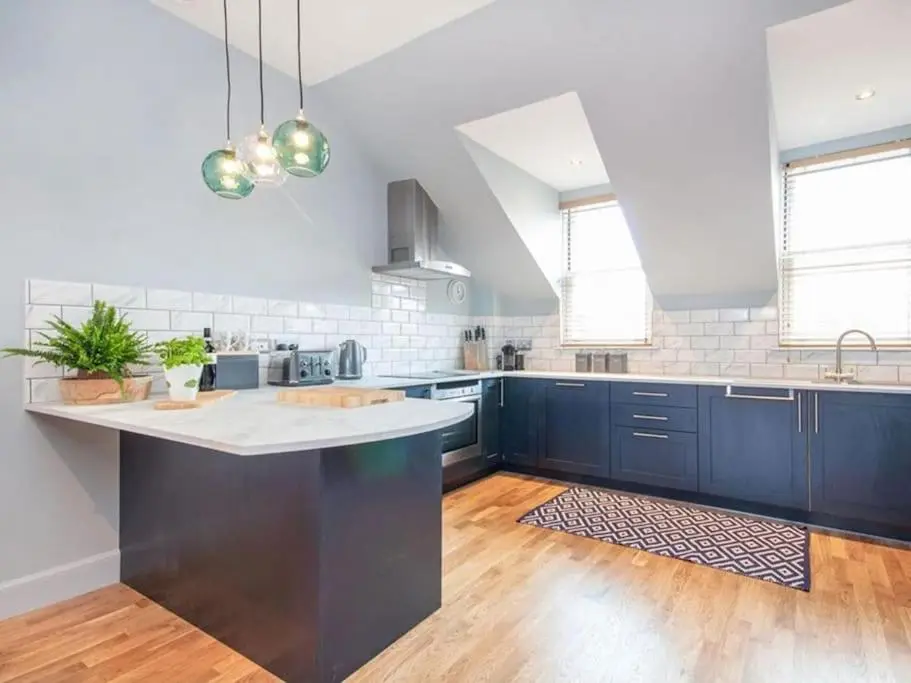 a kitchen with blue cabinets and a large island at Townhouse on the Square, Dornoch in Dornoch