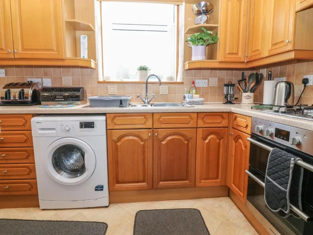 a kitchen with a washing machine and a sink at Thain House in Banff