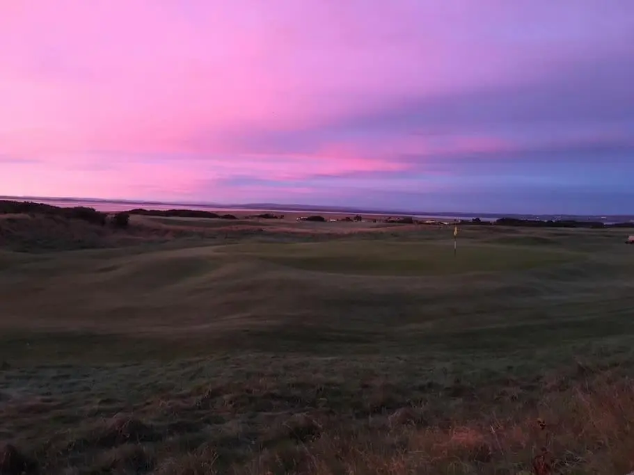 a view of a golf course with a sunset at Orcadia Sutherland Road Dornoch IV25 3SX in Dornoch