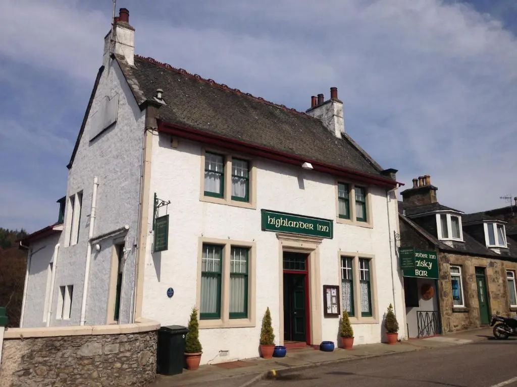 a white building on the corner of a street at Highlander Inn in Craigellachie
