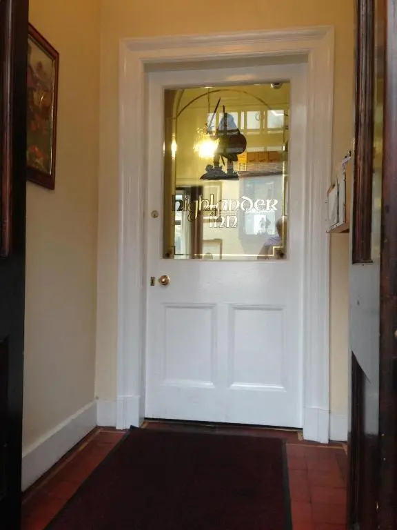a white door with a window in a hallway at Highlander Inn in Craigellachie
