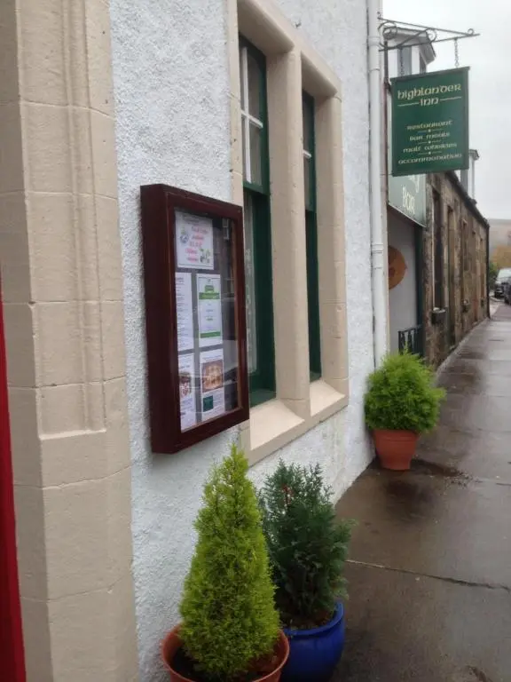a building with potted trees on the side of it at Highlander Inn in Craigellachie