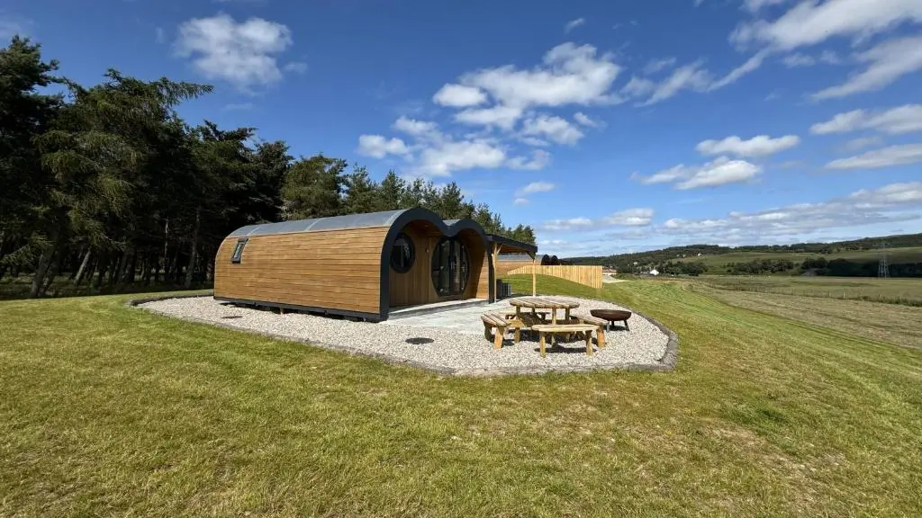 a wooden cabin with a picnic table in a field at Juniper Lodges in Inverness