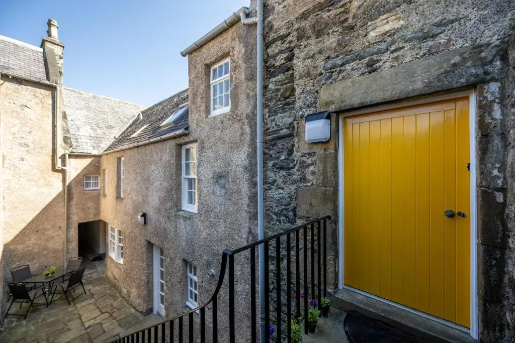 a yellow garage door in an old stone building at 7 Shorehead, Portsoy in Portsoy