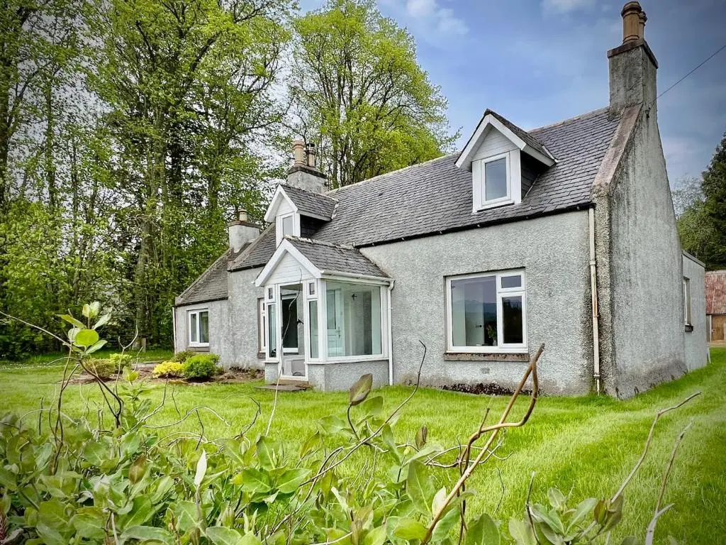an old house with a grass field in front of it at Cosy Country House in Deeside in Finzean