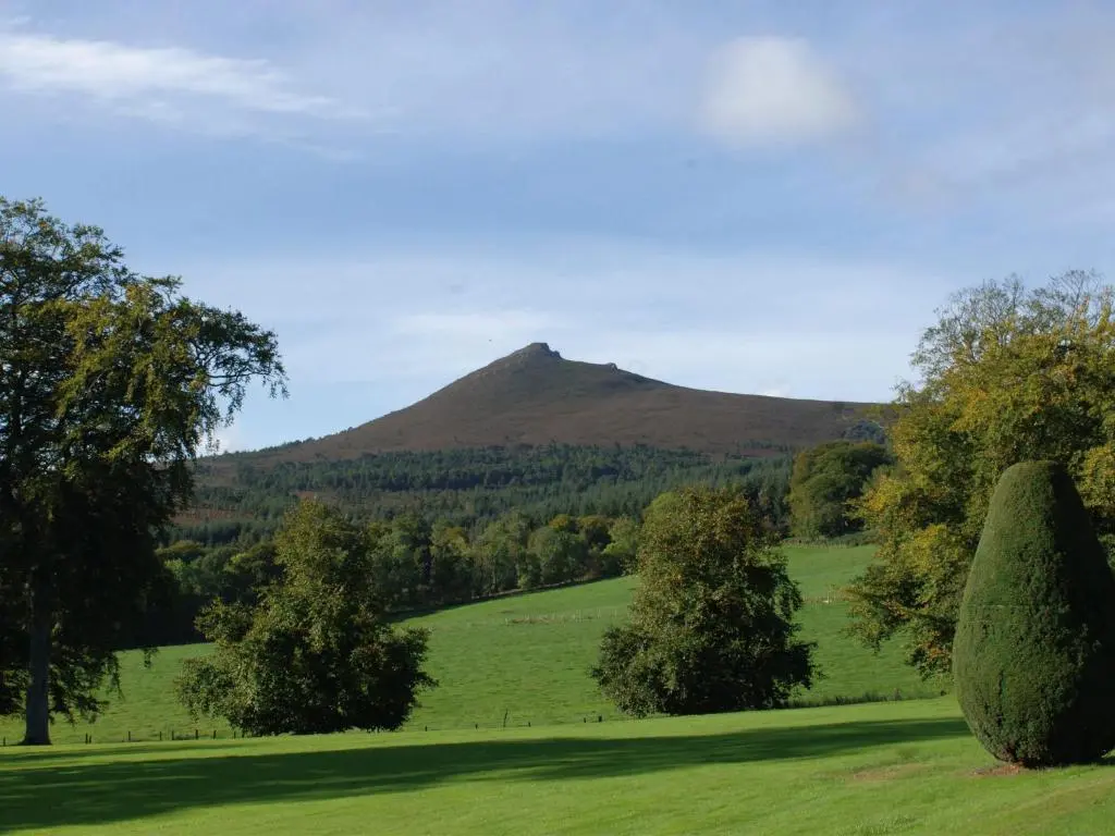 a green field with a mountain in the background at Macdonald Pittodrie House in Chapel of Garioch