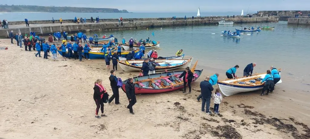 a group of people standing on a beach with boats at A cosy seaside cottage in Cullen