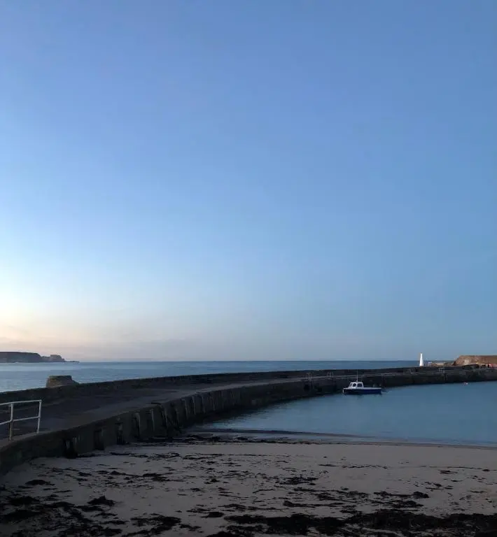 a boat in the water next to a pier at A cosy seaside cottage in Cullen