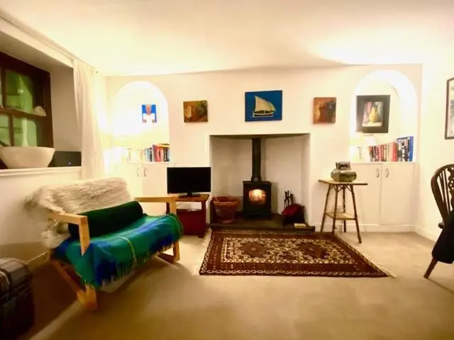 a living room with a couch and a fireplace at A cosy seaside cottage in Cullen