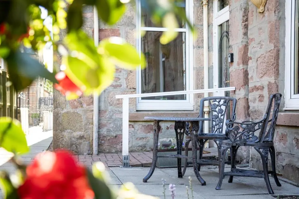 a table and chairs on the porch of a building at Lachie's Townhouse in Inverness