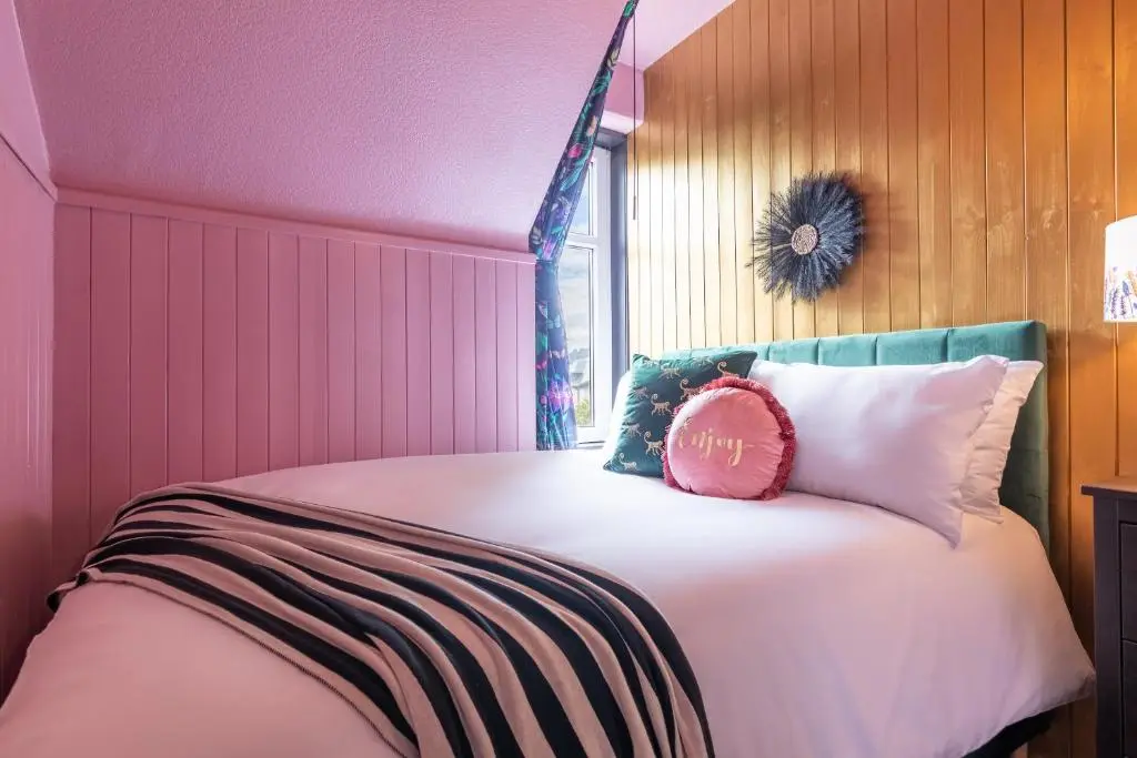 a pink bedroom with a bed with a pink pillow on it at Lachie's Townhouse in Inverness