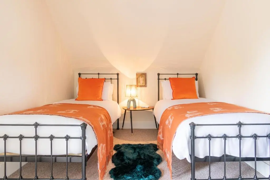 two beds in a room with orange and white at Lachie's Townhouse in Inverness
