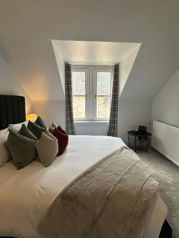 a bedroom with a large white bed with a window at Haugh Hideaway in Inverness