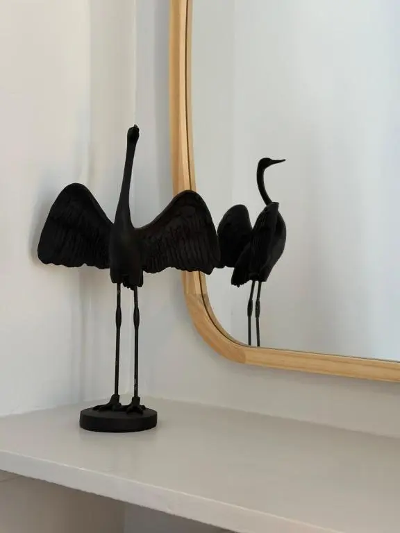a black bird statue on a shelf next to a mirror at Haugh Hideaway in Inverness