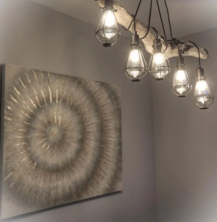 a group of lights hanging from a ceiling with a painting at Otago Cottage, Brora in Brora