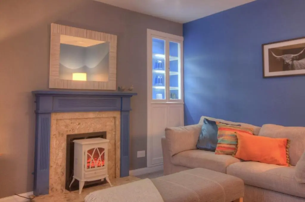 a living room with a couch and a fireplace at Otago Cottage, Brora in Brora