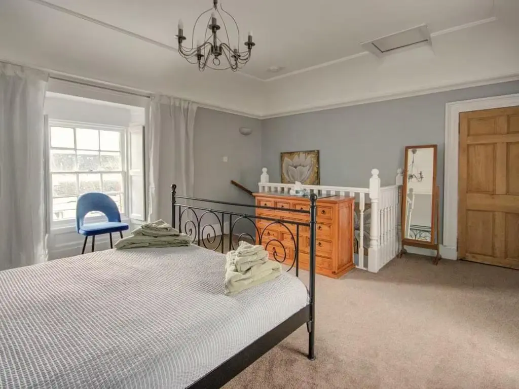 a bedroom with a bed and a blue chair at Anvil House, Golspie in Golspie