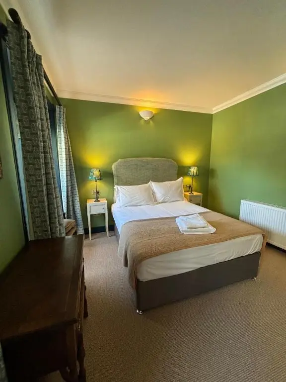 a bedroom with a large bed with green walls at Hootananny in Inverness