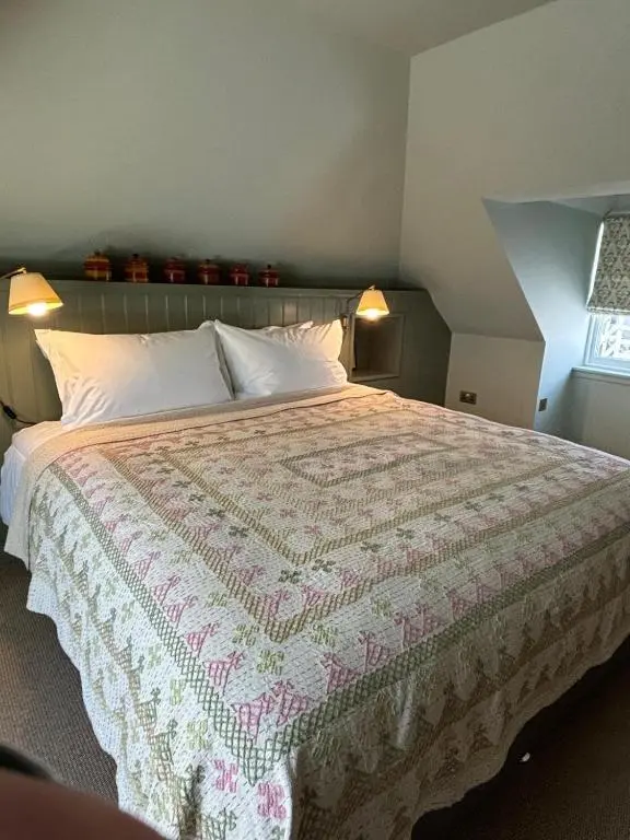 a bedroom with a bed with a pink and white quilt at Hootananny in Inverness
