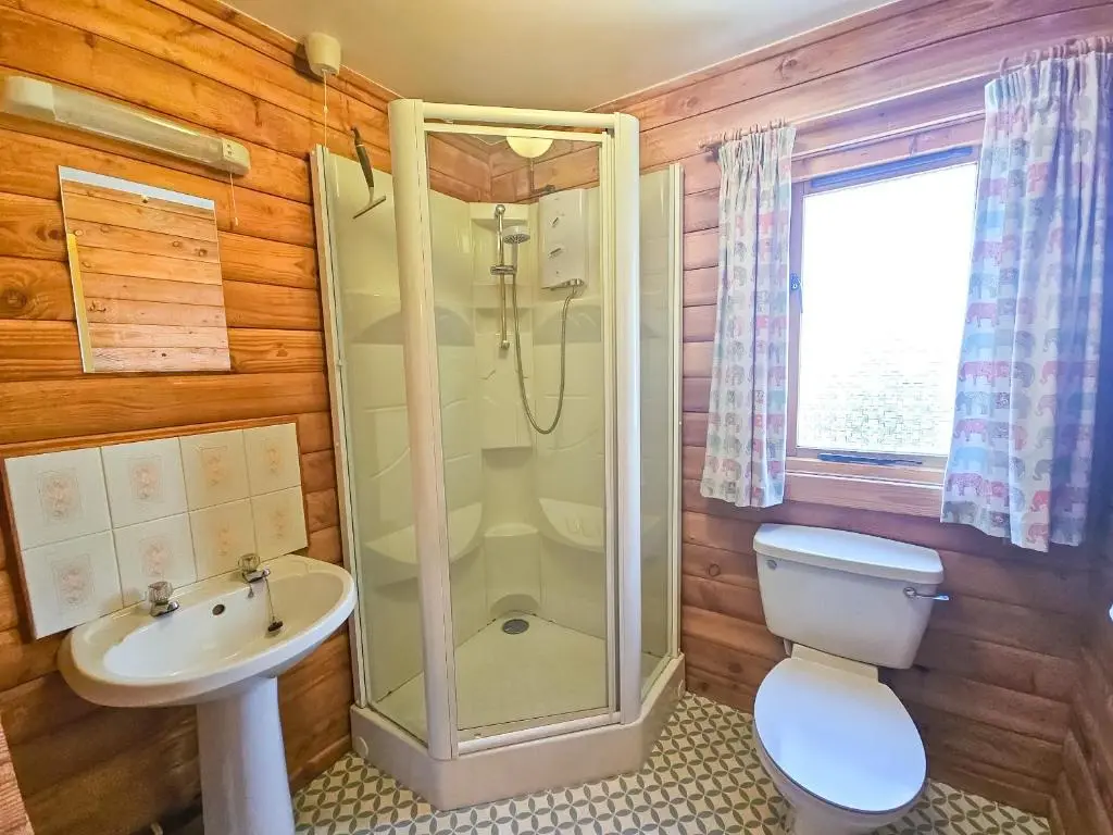 a bathroom with a shower and a toilet and a sink at Balbeag Cottage in Insh