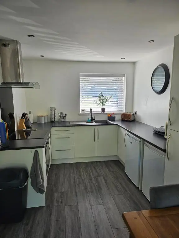 a kitchen with white cabinets and a sink and a window at 5 Fulmar Road**Next to West Beach and Golf Course in Lossiemouth