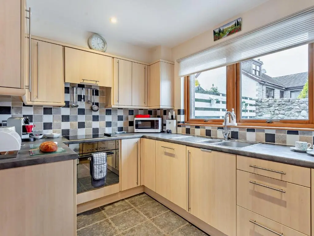 a kitchen with wooden cabinets and a sink and a window at 3 Bed in Grantown-on-Spey 94514 in Grantown on Spey