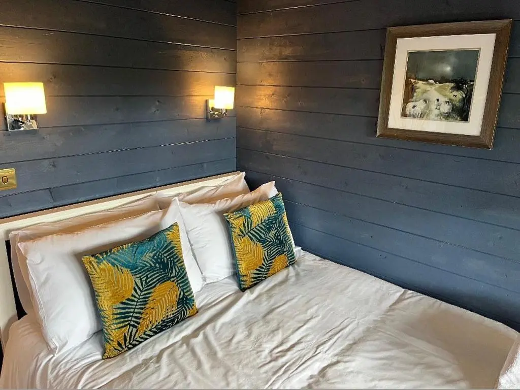 a bed in a room with two pillows at Retreat Hot Tub Highland Cabin in Inverness