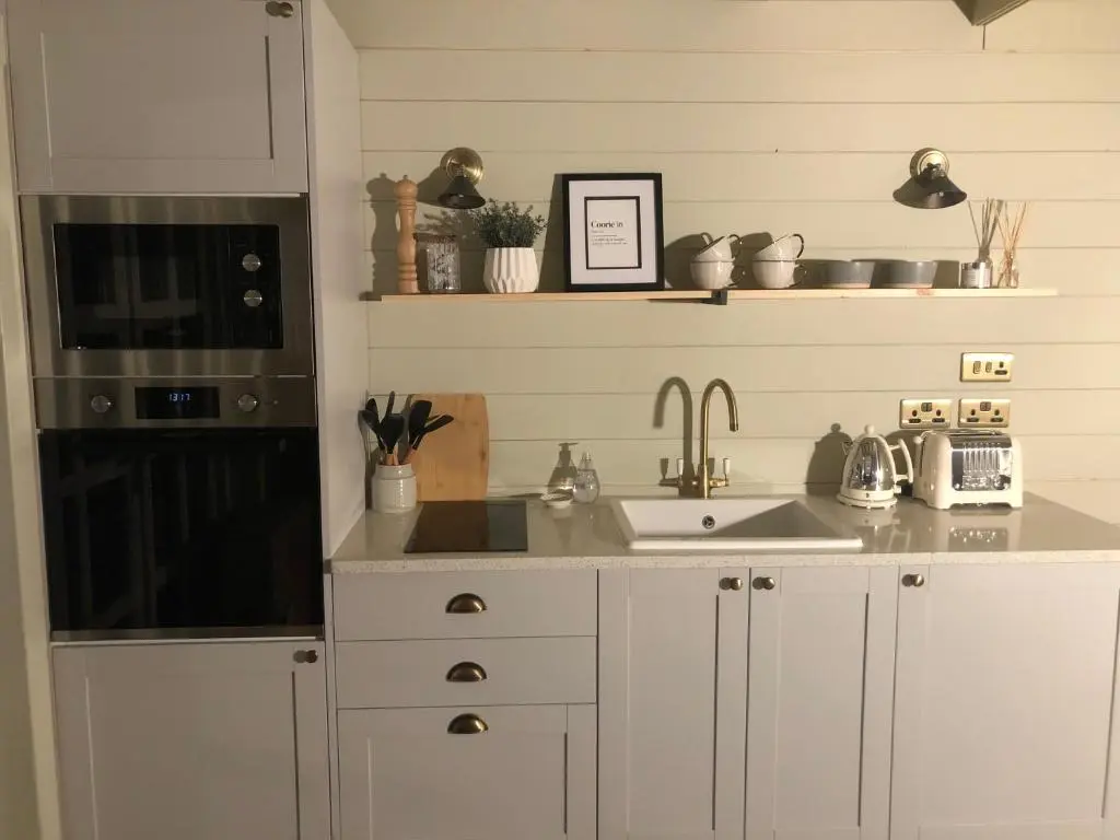 a kitchen with white cabinets and a sink at Retreat Hot Tub Highland Cabin in Inverness
