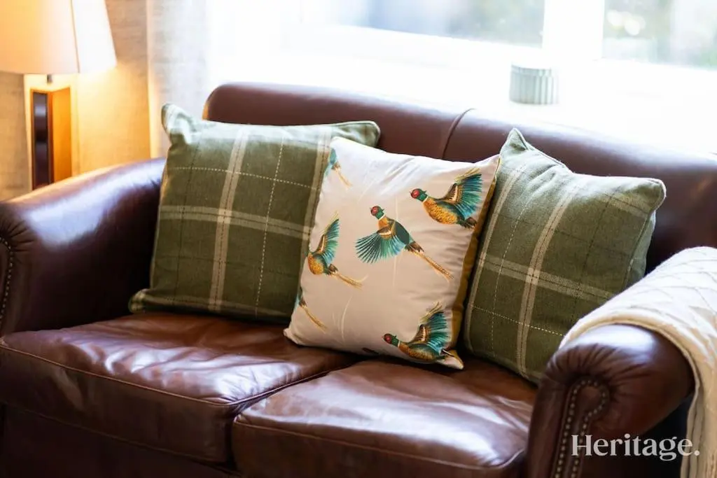 a brown leather couch with four pillows on it at Station Cottage Dinnet, Aboyne in Aboyne