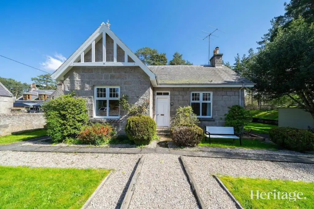 a stone house with a bench in front of it at Station Cottage Dinnet, Aboyne in Aboyne