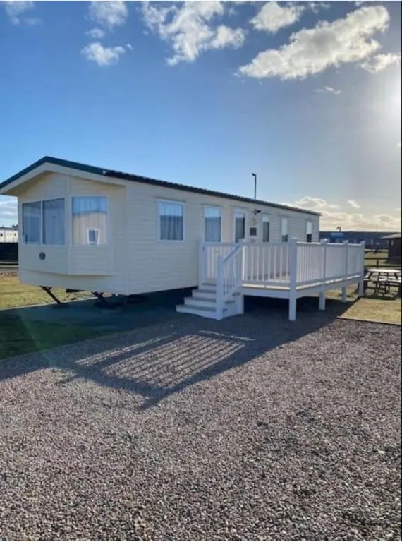 a large white house with a porch and a porch at Cozy\u2019s caravan hire in Lossiemouth