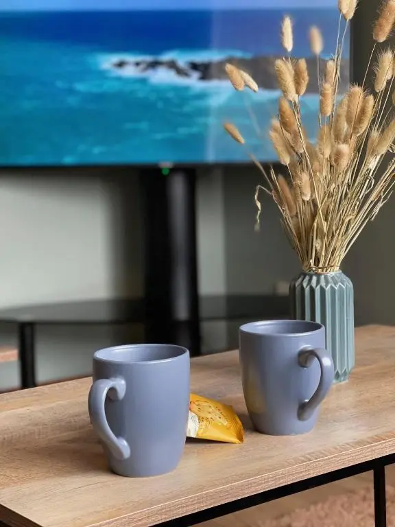 two coffee cups on a wooden table with a vase at Meggies Place in Inverness