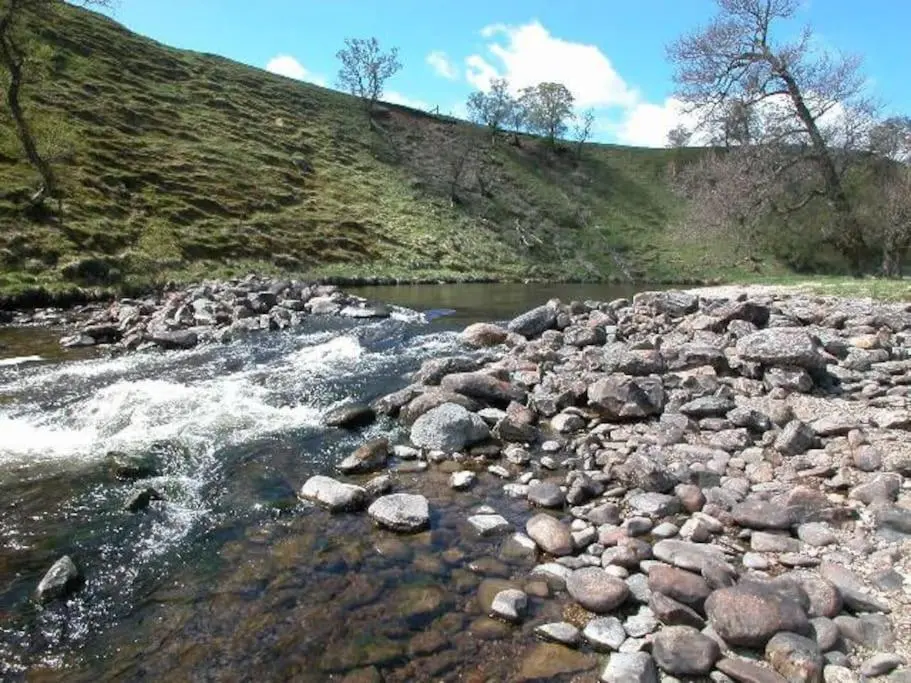 a river with rocks and water and a hill at Cray House - Large Country Home in Perthshire in Cray