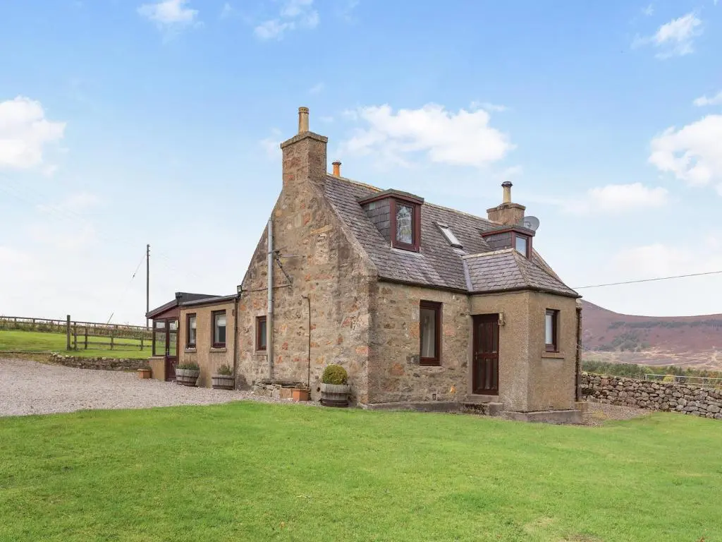 an old stone house with a green lawn at Mid Bellandy in Ballindalloch