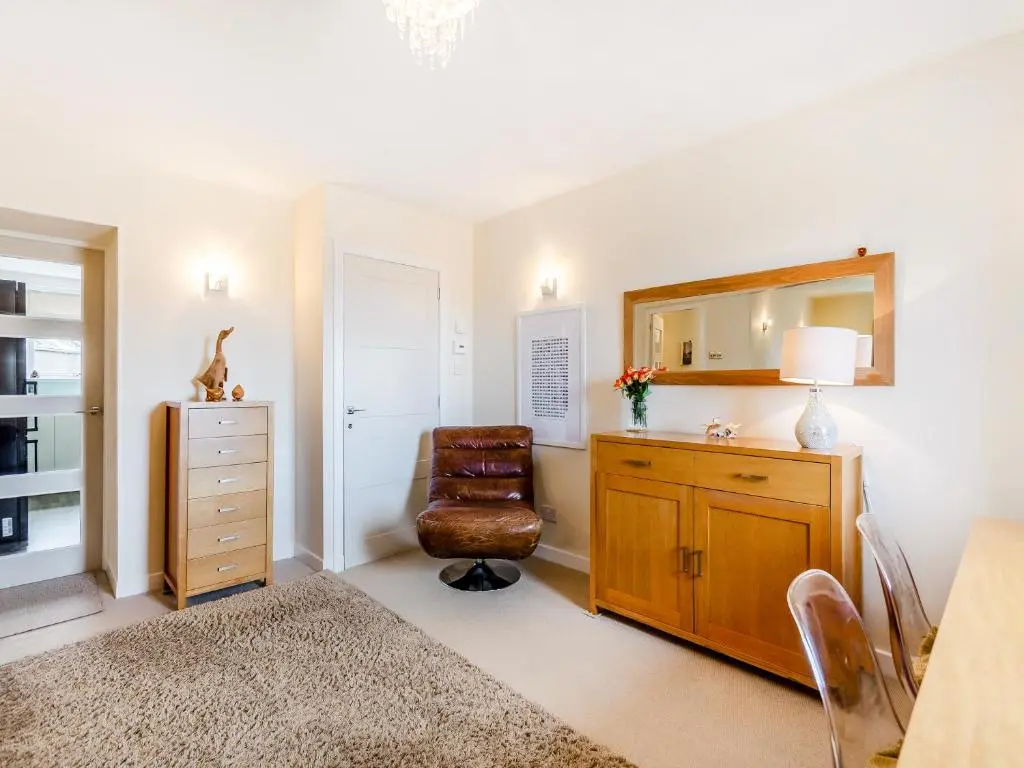 a room with a chair and a dresser and a mirror at Mid Bellandy in Ballindalloch