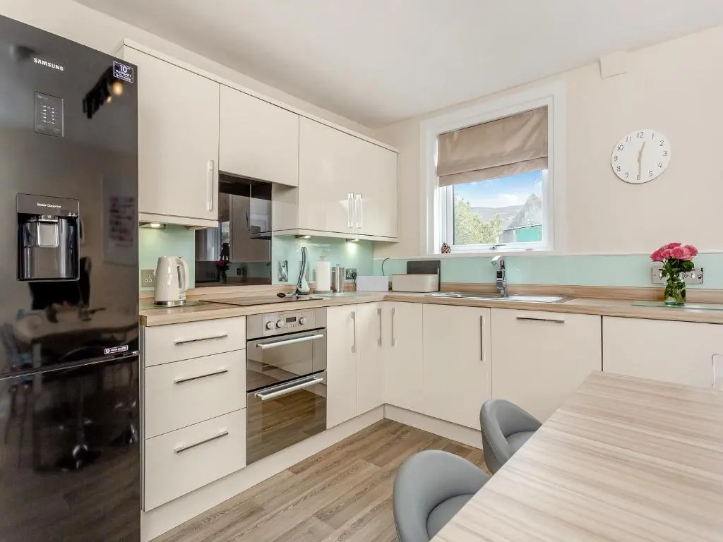 a kitchen with white cabinets and a table and a window at Mid Bellandy in Ballindalloch