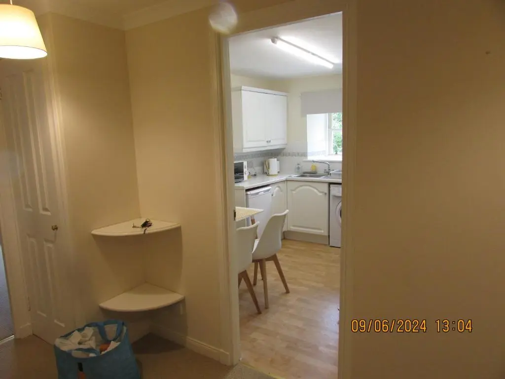 a kitchen with white cabinets and a table and chairs at Culloden Stables 4 in Inverness