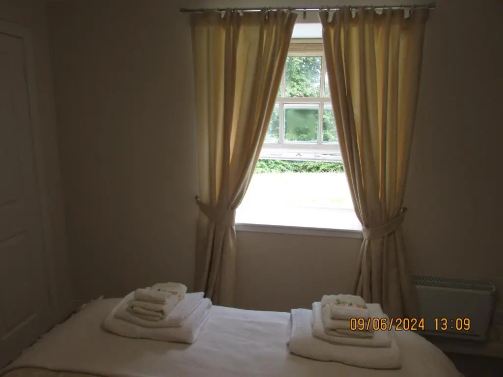 a bedroom with a bed and a window with towels at Culloden Stables 4 in Inverness